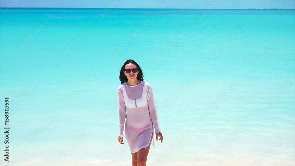 Young beautiful woman on white tropical beach. Girl having fun on her summer vacation. SLOW MOTION Young beautiful woman on white tropical beach. Girl having fun on her summer vacation. SLOW MOTION