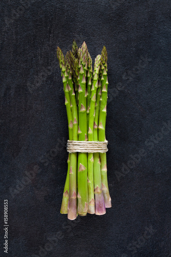 Bunch of green fresh asparagus isolated on dark gray slate