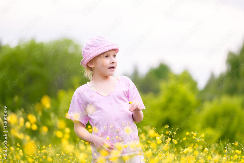 Adorable blonde girl in pink hat and clothes posing on sunset on meadow with flowers Adorable blonde girl in pink hat and clothes posing on sunset on meadow with flowers