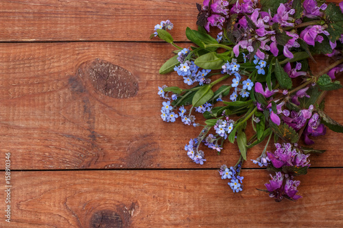 brown wooden background with bunch of forget-me-nots  and dead-nettle