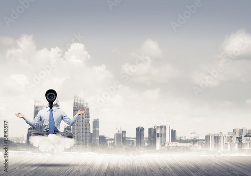 Camera headed man sitting in lotus pose on cloud against modern 