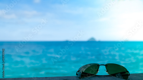Single sunglasses on tropical sea background with flare effect