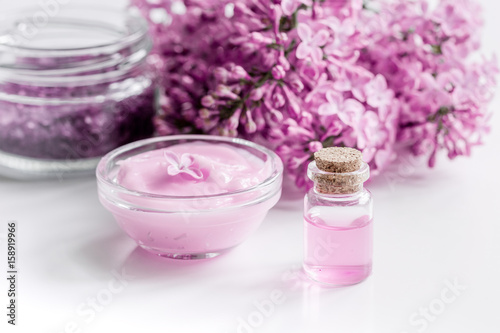 lilac cosmetics with flowers and spa set on white table background