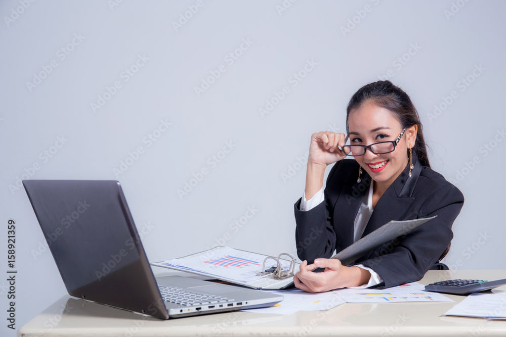 Businesswoman sitting at desk in office. He looks at the camera and smiling. Businesswoman sitting at desk in office. He looks at the camera and smiling.