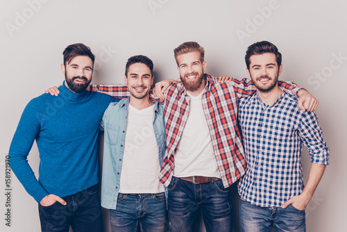 Diversity of men. Four cheerful young guys are standing and embracing, smiling, on pure background in casual outfit and jeans photo