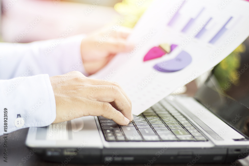 Businessman looking graph paper of finance, account and business with notebook on table Businessman looking graph paper of finance, account and business with notebook on table
