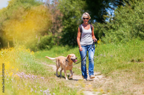 Cuadro en lienzo mature woman hiking with dog in the landscape