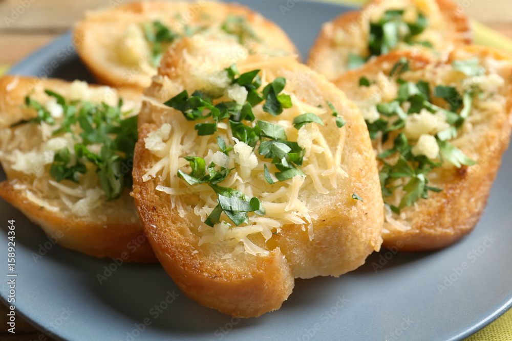 Tasty bread slices with grated cheese, garlic and herbs on plate Tasty bread slices with grated cheese, garlic and herbs on plate