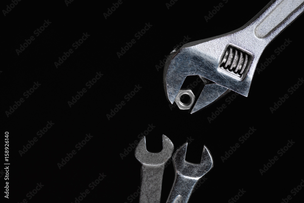 One adjustable wrench, two feeds a spanner nut on a black background One adjustable wrench, two feeds a spanner nut on a black background