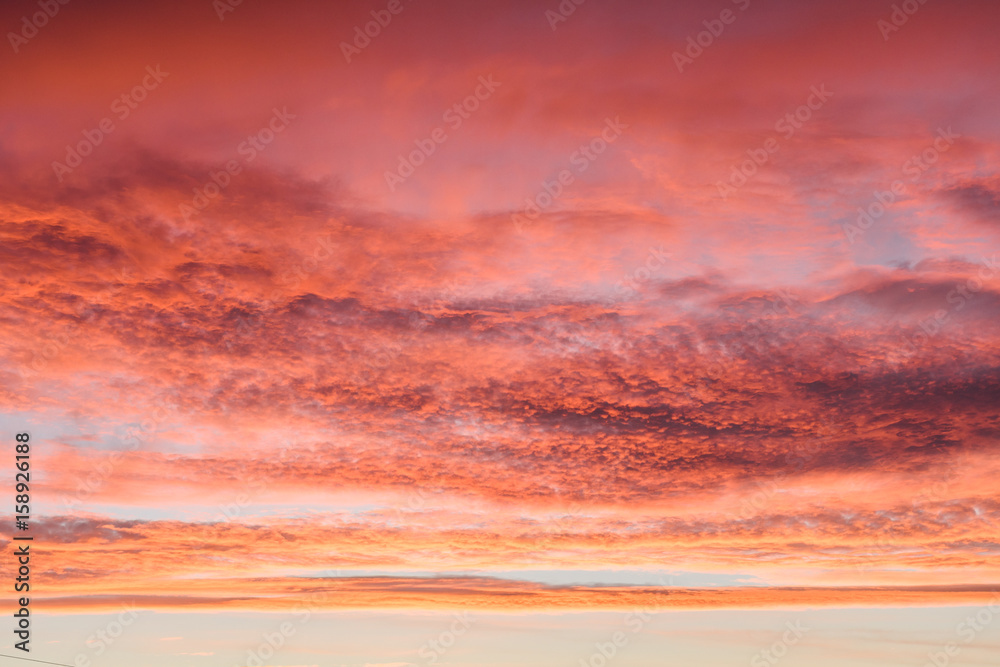 Obraz premium Beautiful fiery sunset sky with clouds painted in all shades of pink and orange
