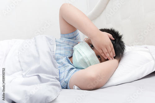 sick boy with hygienic mask lie down on bed