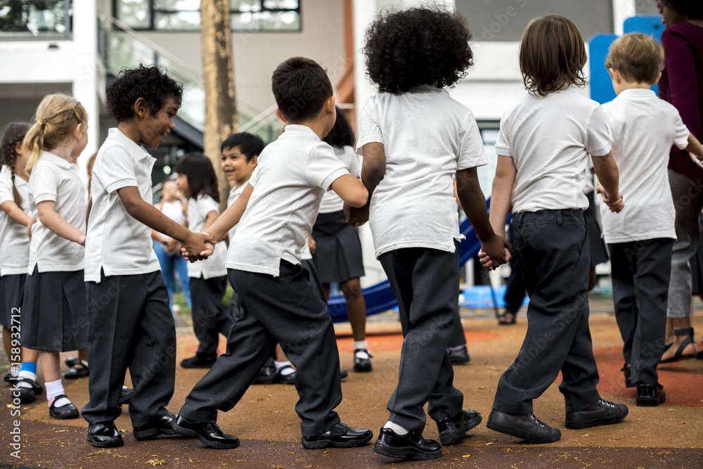 Fototapeta premium Group of diverse kindergarten students standing holding hands together