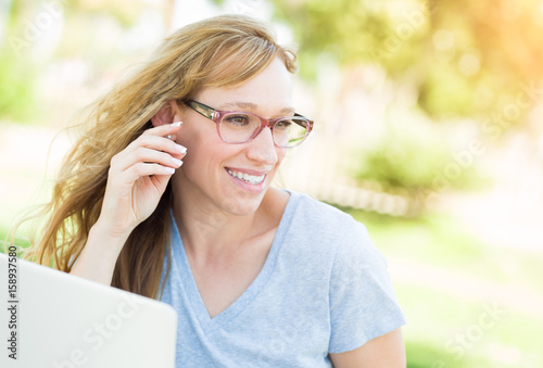 Young Adult Woman Wearing Glasses Outdoors Using Her Laptop.