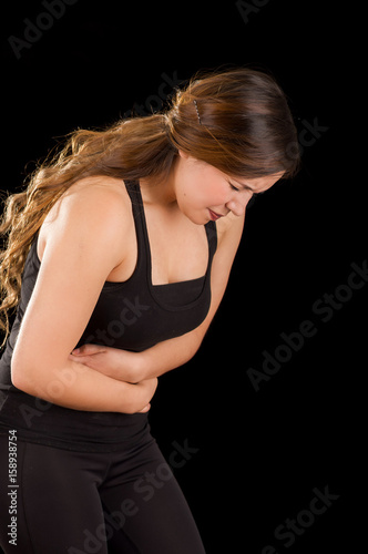 Beautiful young woman with stomach ache or nausea in a black background photo