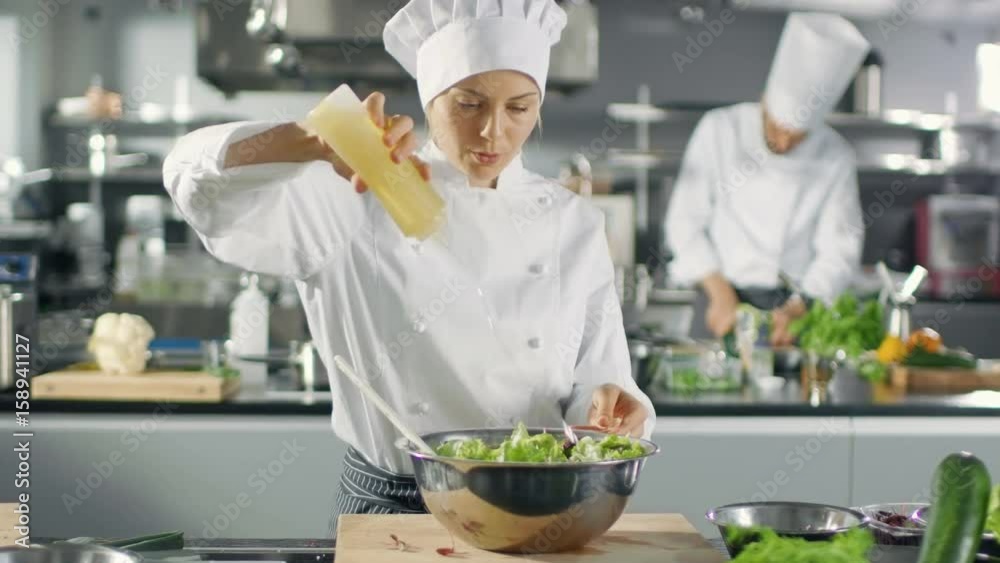 In a Famous Restaurant Female Cook Prepares Salad, ads Oil. She Works in a Big Modern Kitchen. Shot on RED EPIC-W 8K Helium Cinema Camera. In a Famous Restaurant Female Cook Prepares Salad, ads Oil. She Works in a Big Modern Kitchen. Shot on RED EPIC-W 8K Helium Cinema Camera.