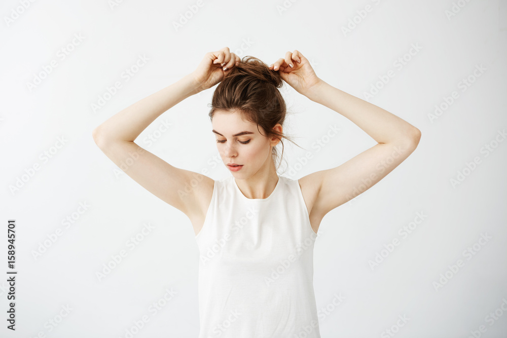 Young beautiful girl correcting hair bun over white background. Young beautiful girl correcting hair bun over white background.