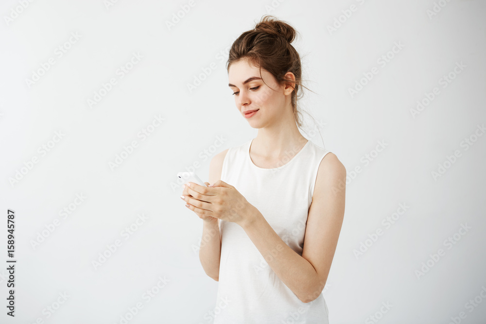 Young pretty girl smiling looking at phone over white background. Young pretty girl smiling looking at phone over white background.