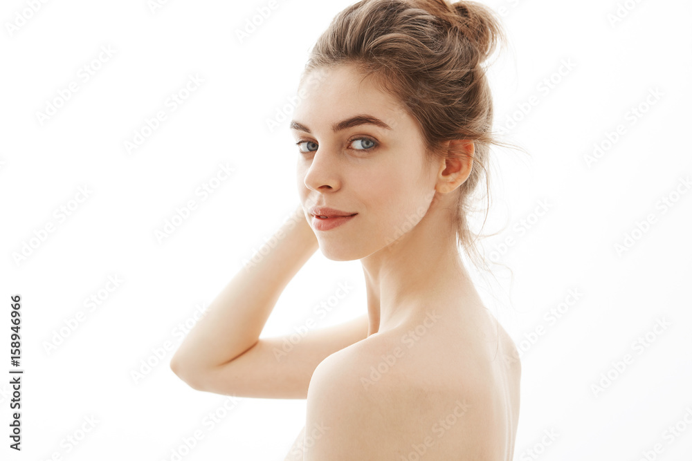 Portrait of young attractive tender naked girl with bun looking at camera over white background. Portrait of young attractive tender naked girl with bun looking at camera over white background.