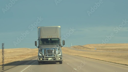 Wallpaper Mural CLOSE UP: Unrecognizable driver steering freight container semi truck hauling goods along the busy multiple lane interstate highway passing through vast prairie grassy fields in Great Plains, America Torontodigital.ca