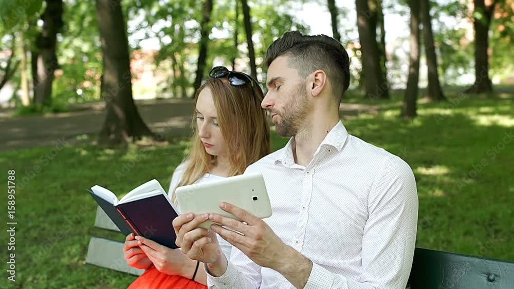 Boy browsing internet on tablet while his girlfriend is reading a book, steadycam shot
Boy browsing internet on tablet while his girlfriend is reading a book, steadycam shot
