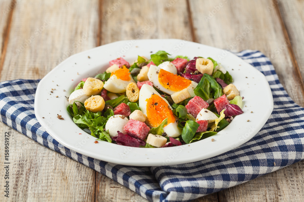 Delicious Italian salad with salami, egg, crostini and mozzarella. Delicious Italian salad with salami, egg, crostini and mozzarella.