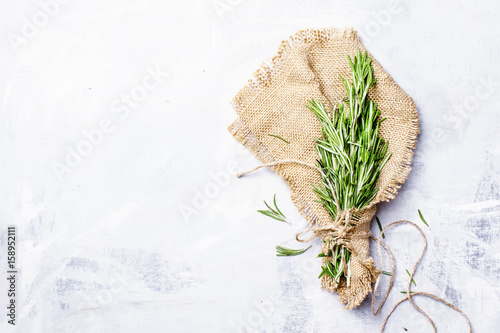 Fresh rosemary in a bundle on a canvas napkin, gray food background, top view photo