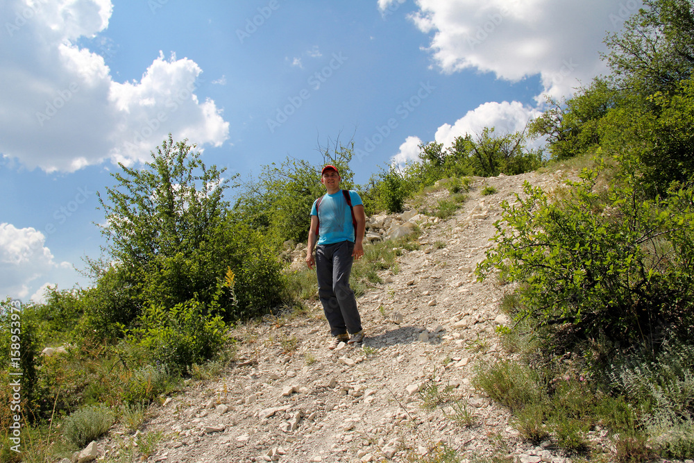 Fototapeta premium young man walks down a hill on a stone road