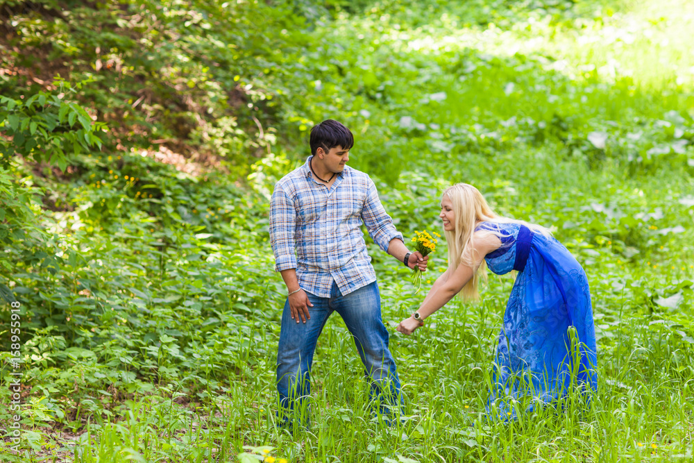 Young man giving a flower dandelion to girlfriend outdoors Young man giving a flower dandelion to girlfriend outdoors