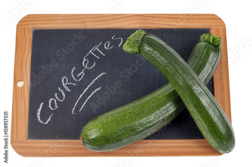 Courgettes écrit sur une ardoise sur laquelle sont posées des courgettes photo