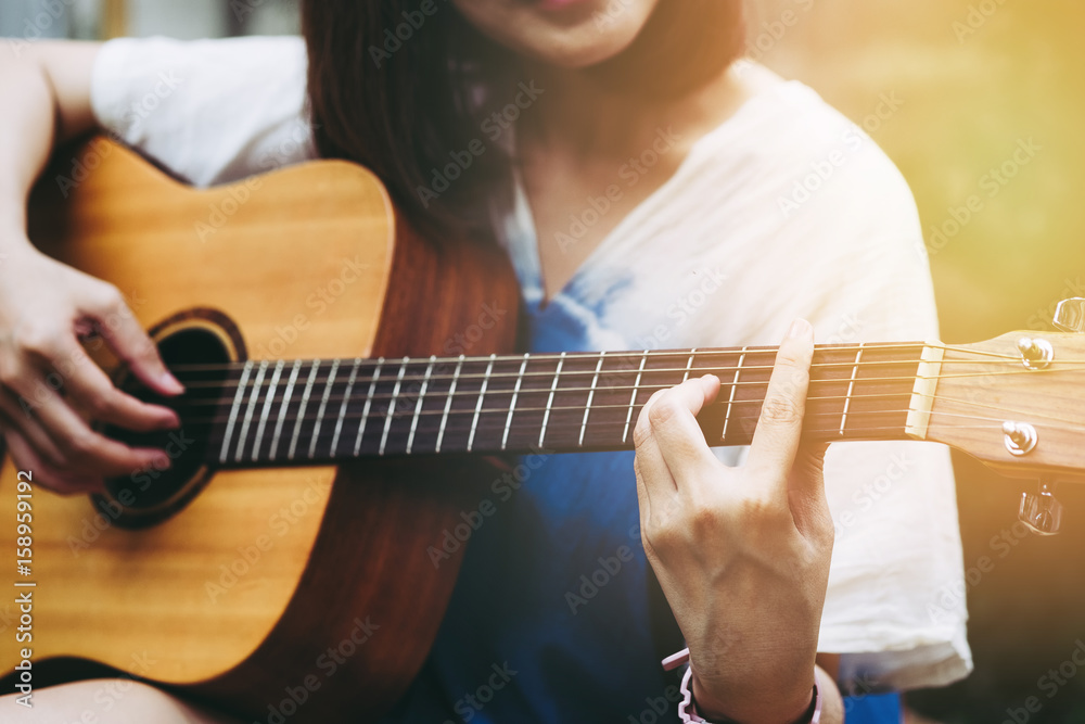 Close up on young woman playing guitar with vintage filter effect