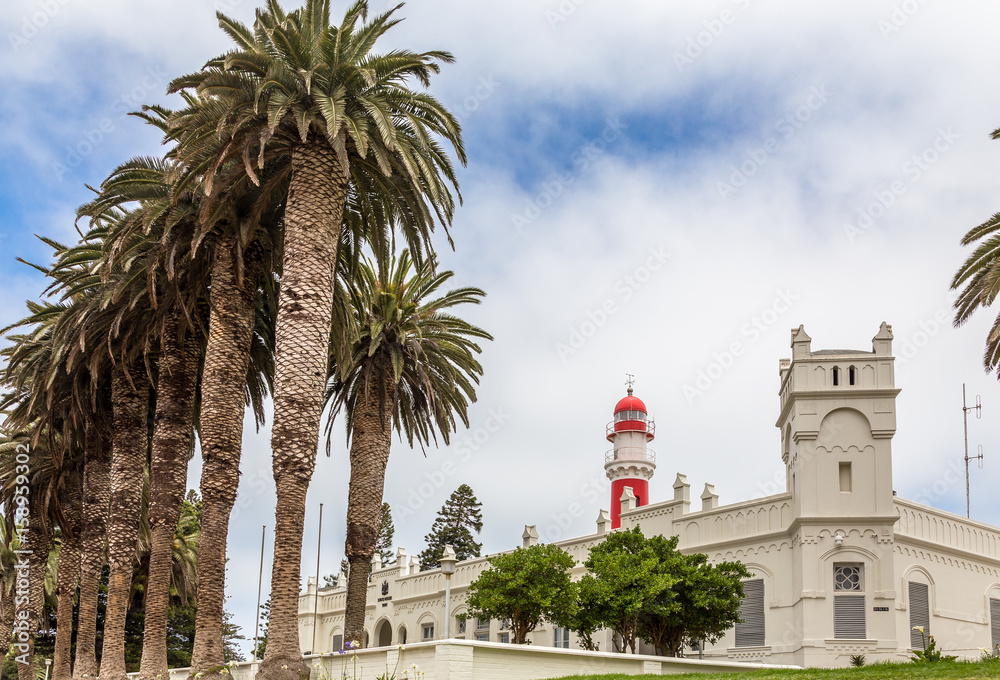 Red lighthouse, white German fort and row of palms, of colonial town of Swakopmund, Namibia
