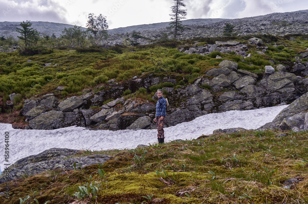 Tourist girl standing near Snowfield summer. the nature of the Urals, the Ural mountains, summer