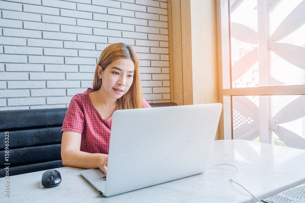 Asian girl working at a coffee shop with a laptop.female freelancer connecting to internet Asian girl working at a coffee shop with a laptop.female freelancer connecting to internet
