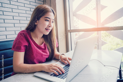 Asian girl working at a coffee shop with a laptop.female freelancer connecting to internet