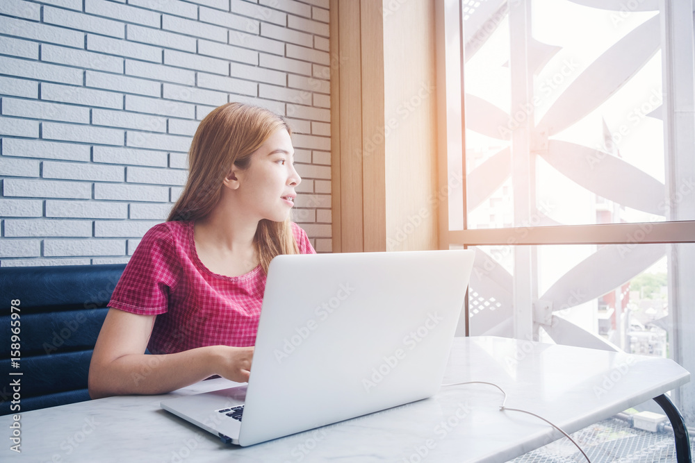 Asian girl working at a coffee shop with a laptop.female freelancer connecting to internet Asian girl working at a coffee shop with a laptop.female freelancer connecting to internet