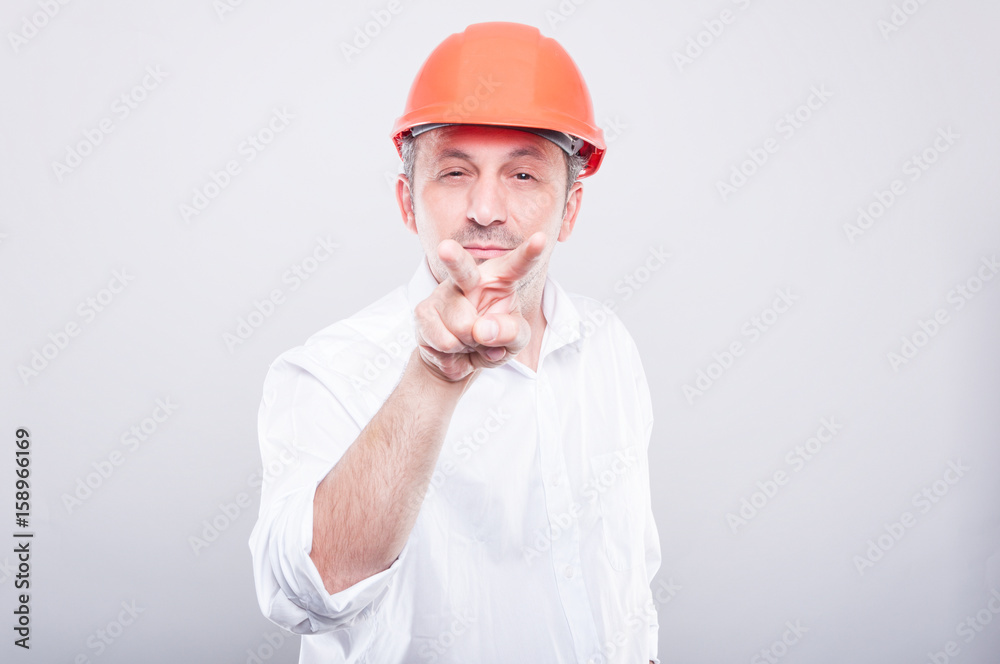 Portrait of architect wearing hardhat making watching you gesture Portrait of architect wearing hardhat making watching you gesture