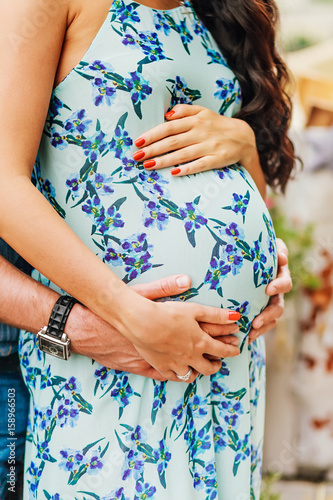 Close-up of human hands holding pregnant belly