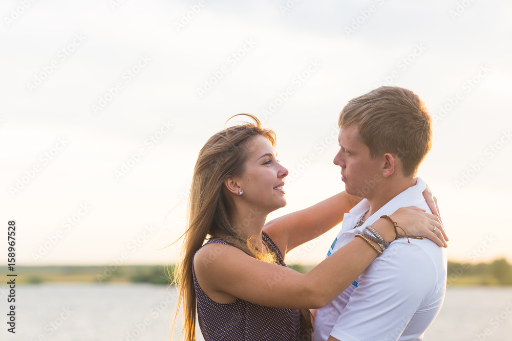 Young couple in love outdoors embracing and laughing together at lake Young couple in love outdoors embracing and laughing together at lake