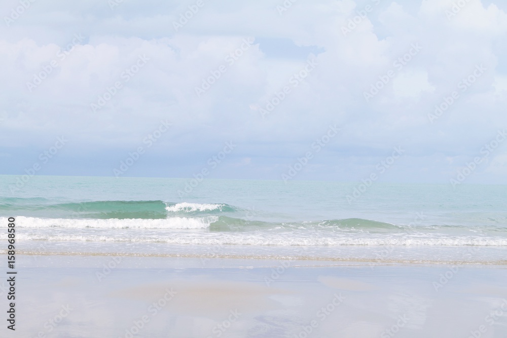 Nature background concept : Sand beach and clear transparent sea wave with foam and blue sky