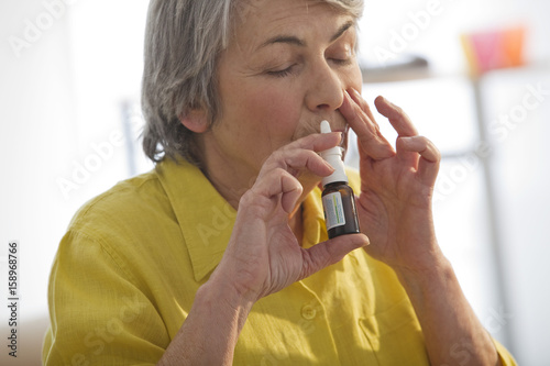Elderly person using nose spray