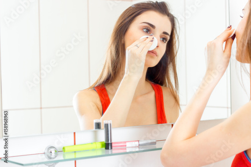 a young woman washes the makeup in the bathroom photo