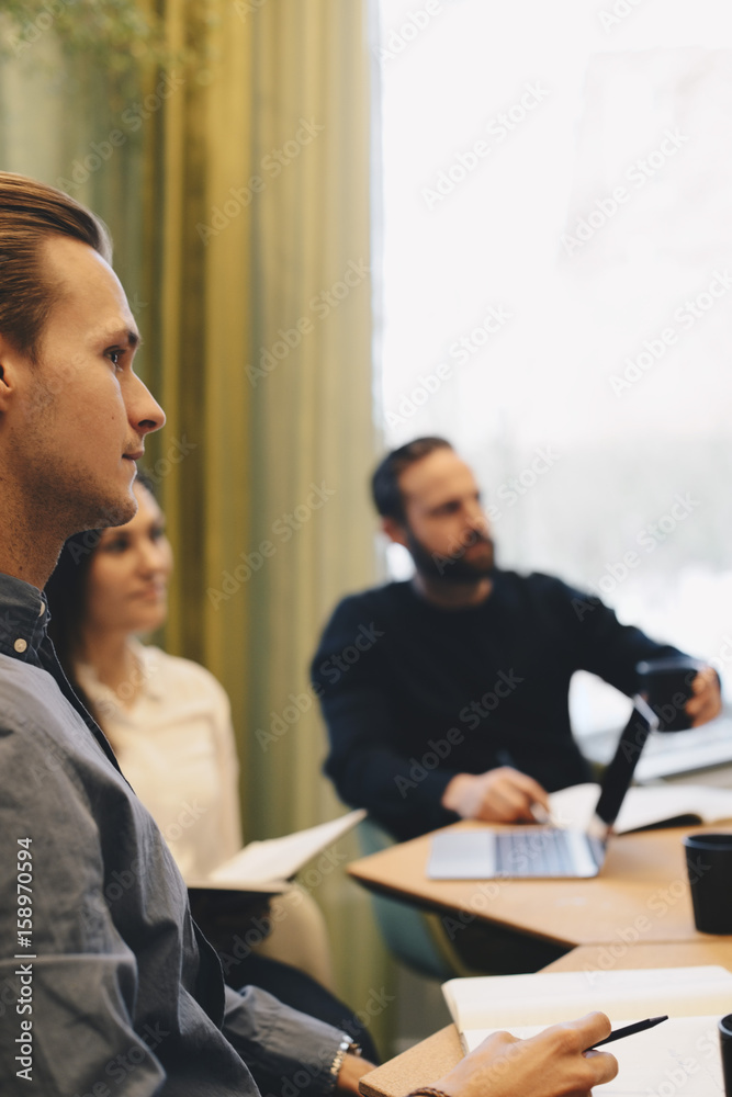 Side view of businessman sitting with colleagues in board room Side view of businessman sitting with colleagues in board room