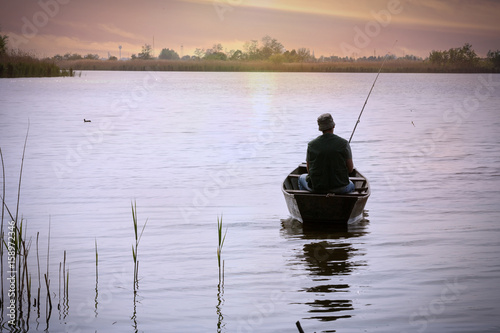 fishing-Fisherman on boat at sunset.