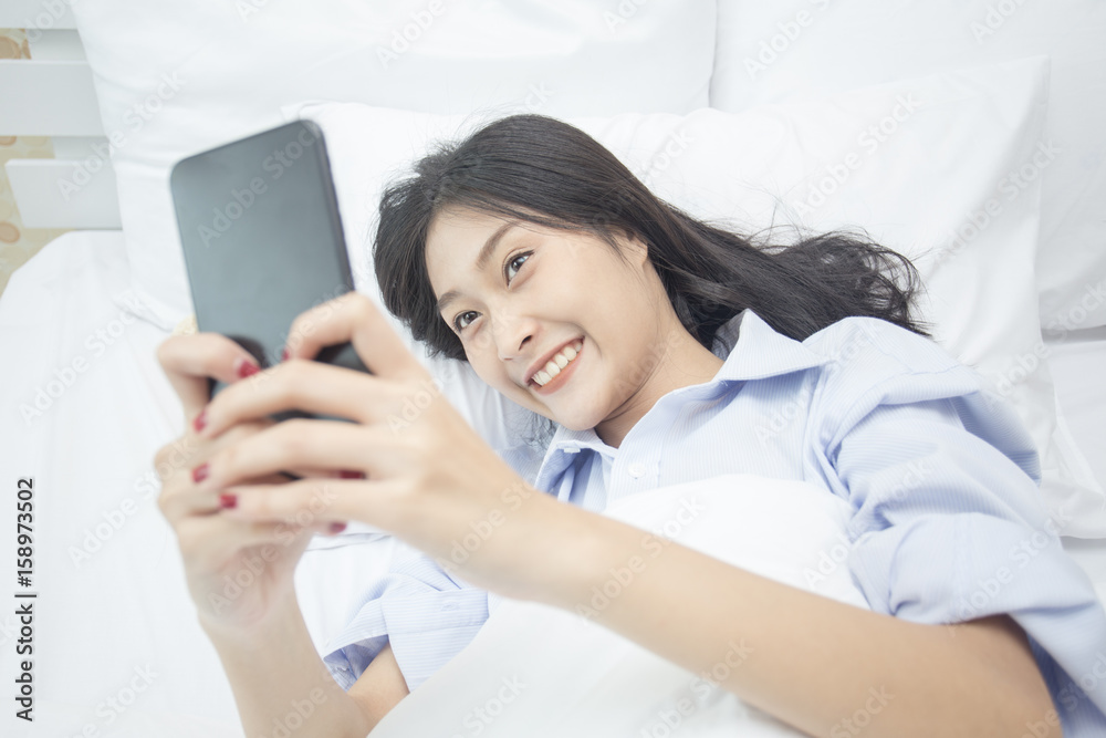 Beautiful young asian woman using smartphone on the bed, 20s year old. Beautiful young asian woman using smartphone on the bed, 20s year old.