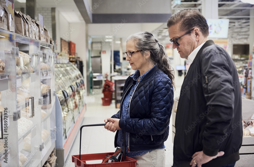Mature couple looking at food cabinet in supermarket Mature couple looking at food cabinet in supermarket