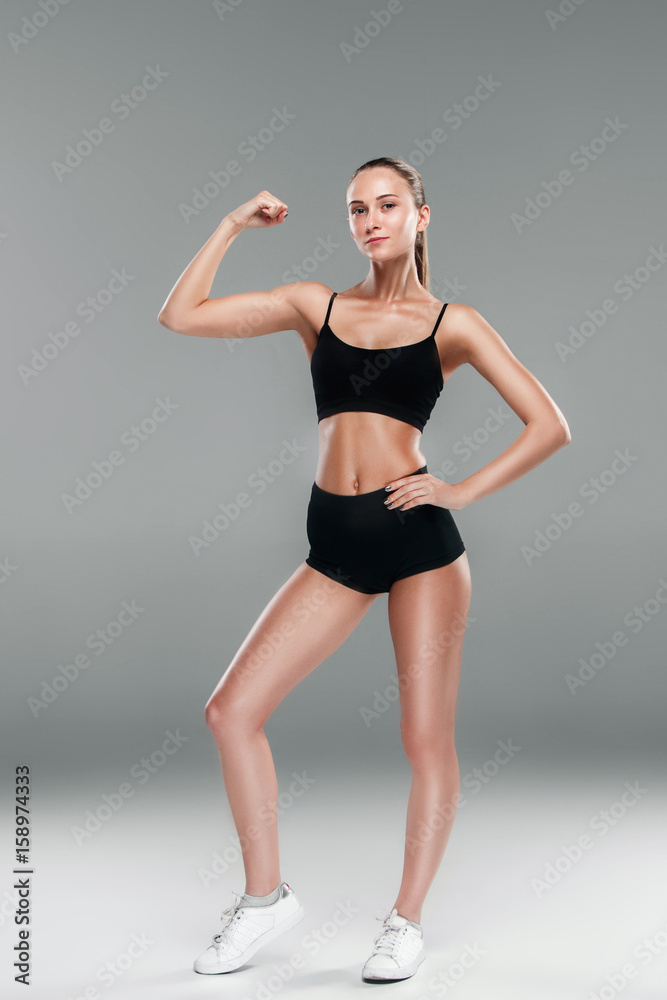 Muscular young woman athlete on gray Muscular young woman athlete on gray