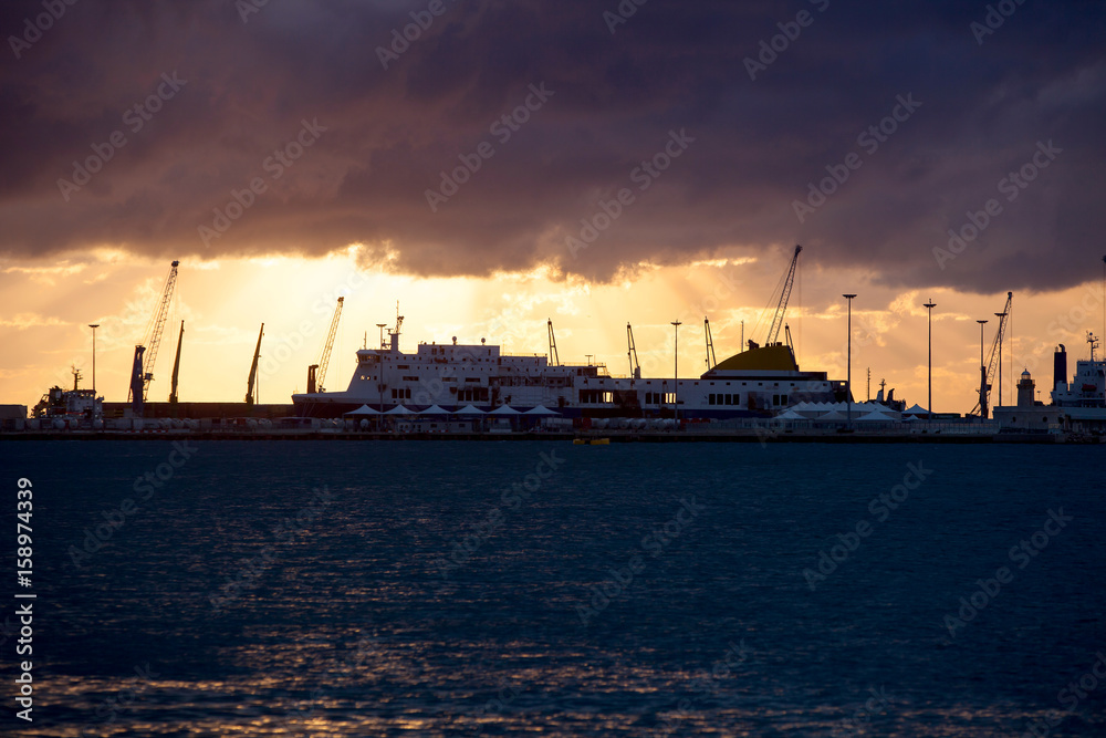 Sea port with big ships and lighthouse at sunset