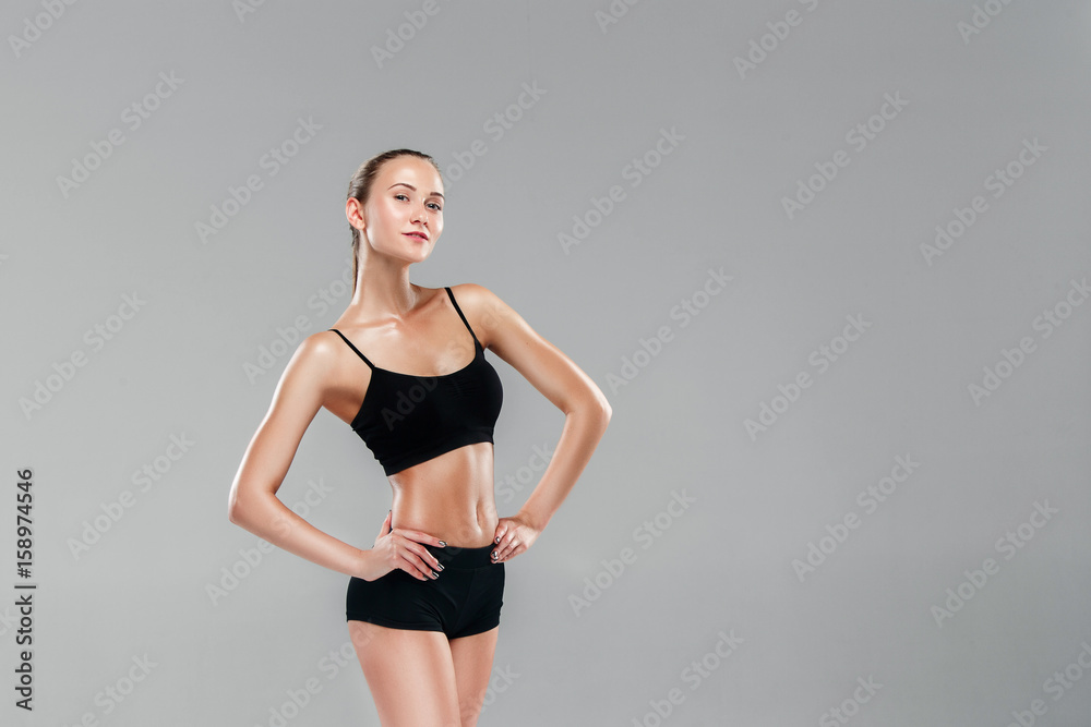 Fototapeta premium Muscular young woman athlete on gray