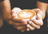 Hands holding hot cup of coffee or tea in morning sunlight