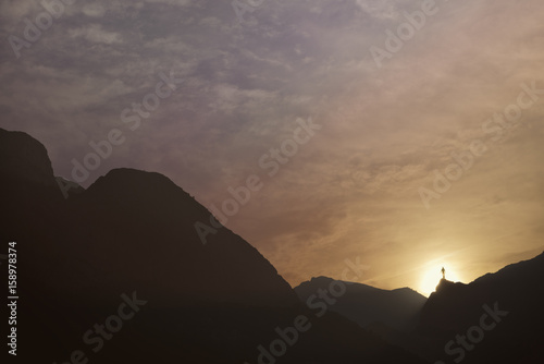 Silhouette of man at the top of the mountain on sunset. Mountain cascade